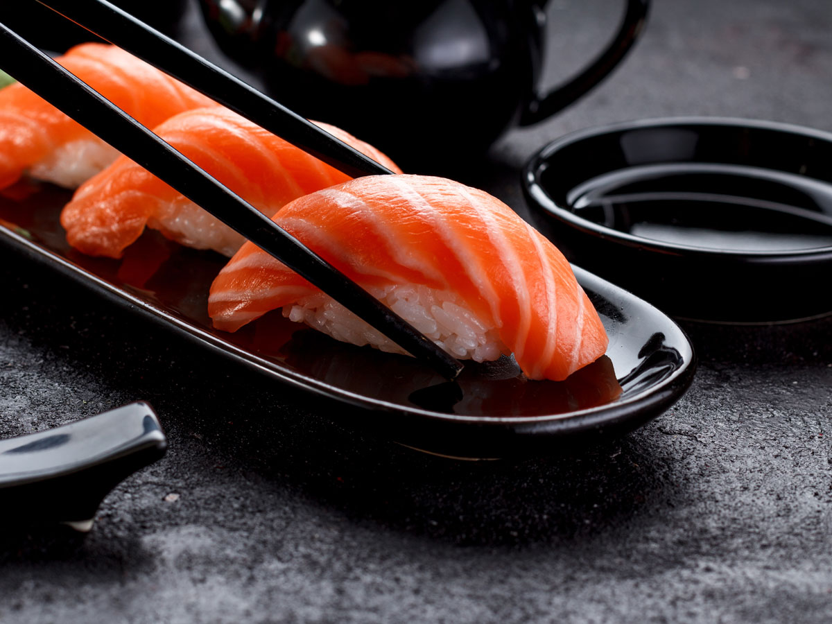 Nahaufnahme von Lachs-Nigiri-Sushi mit Stäbchen